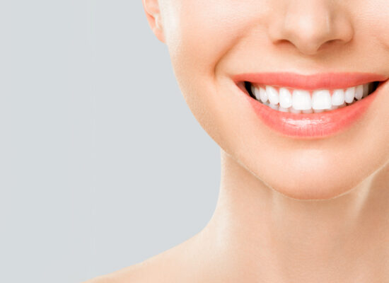 Perfect white teeth smile of a young woman. The result of the teeth whitening procedure. The image symbolizes oral care dentistry, Closeup on a white background.